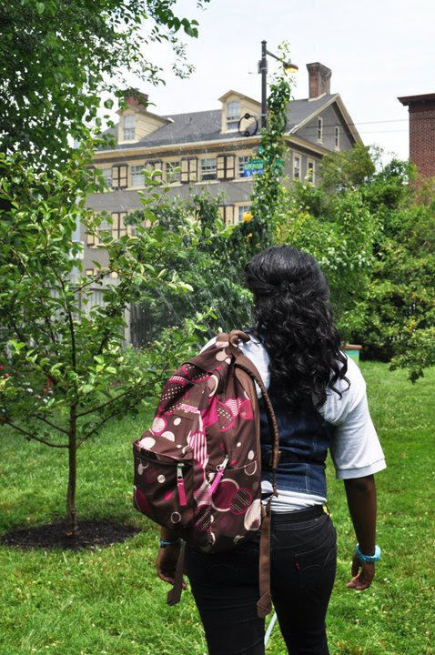 Teenager stands among neighborhood trees. 