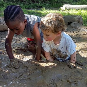 Two young children explore the mud.